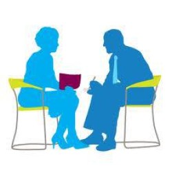 Two figures talking at a table